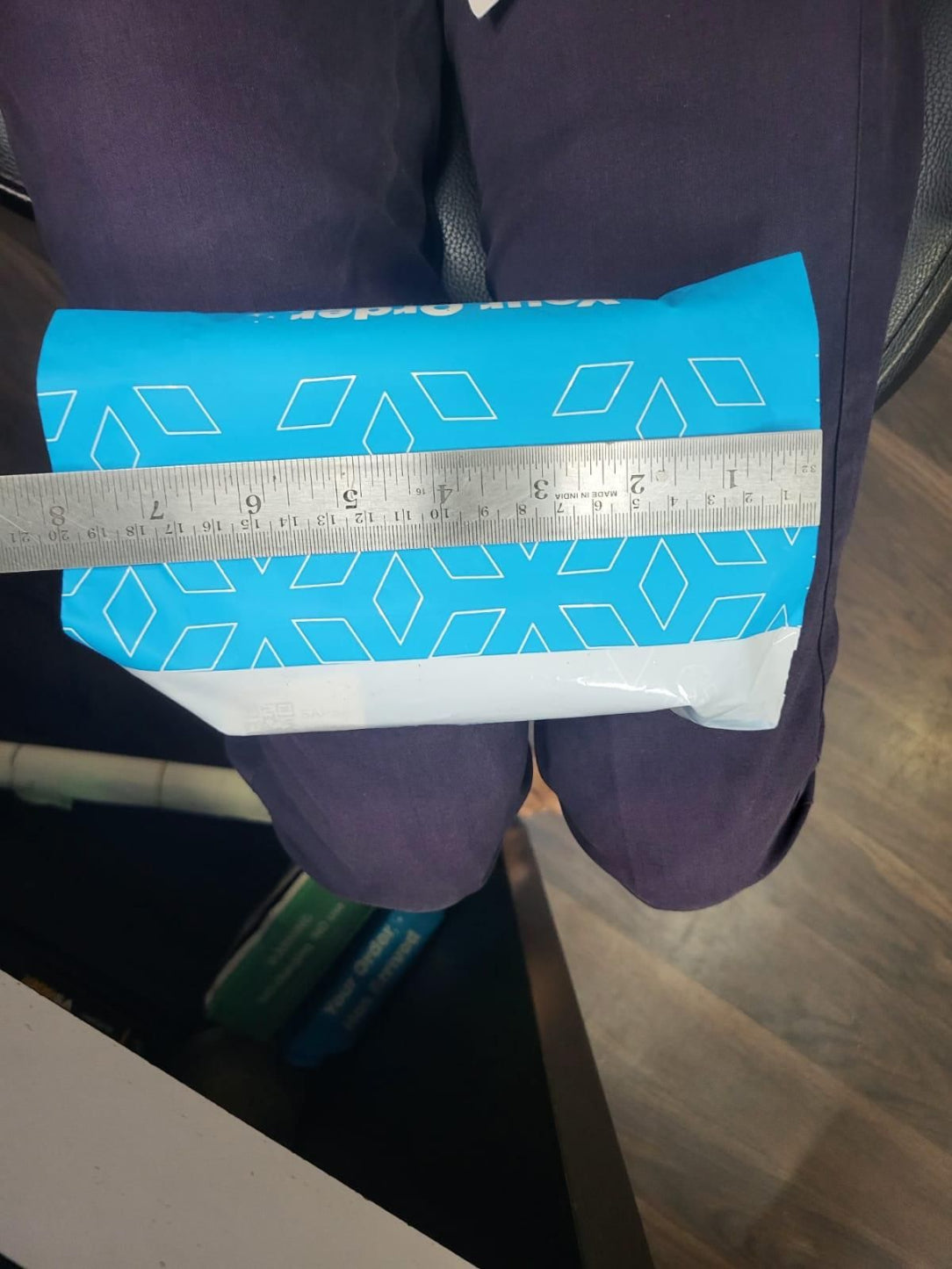 Blue roll of paper with a geometric pattern held by a person, with a ruler for scale.