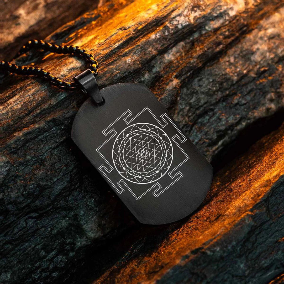 A black chain necklace with a pendant featuring the Shree Yantra design, placed on a textured wooden surface.