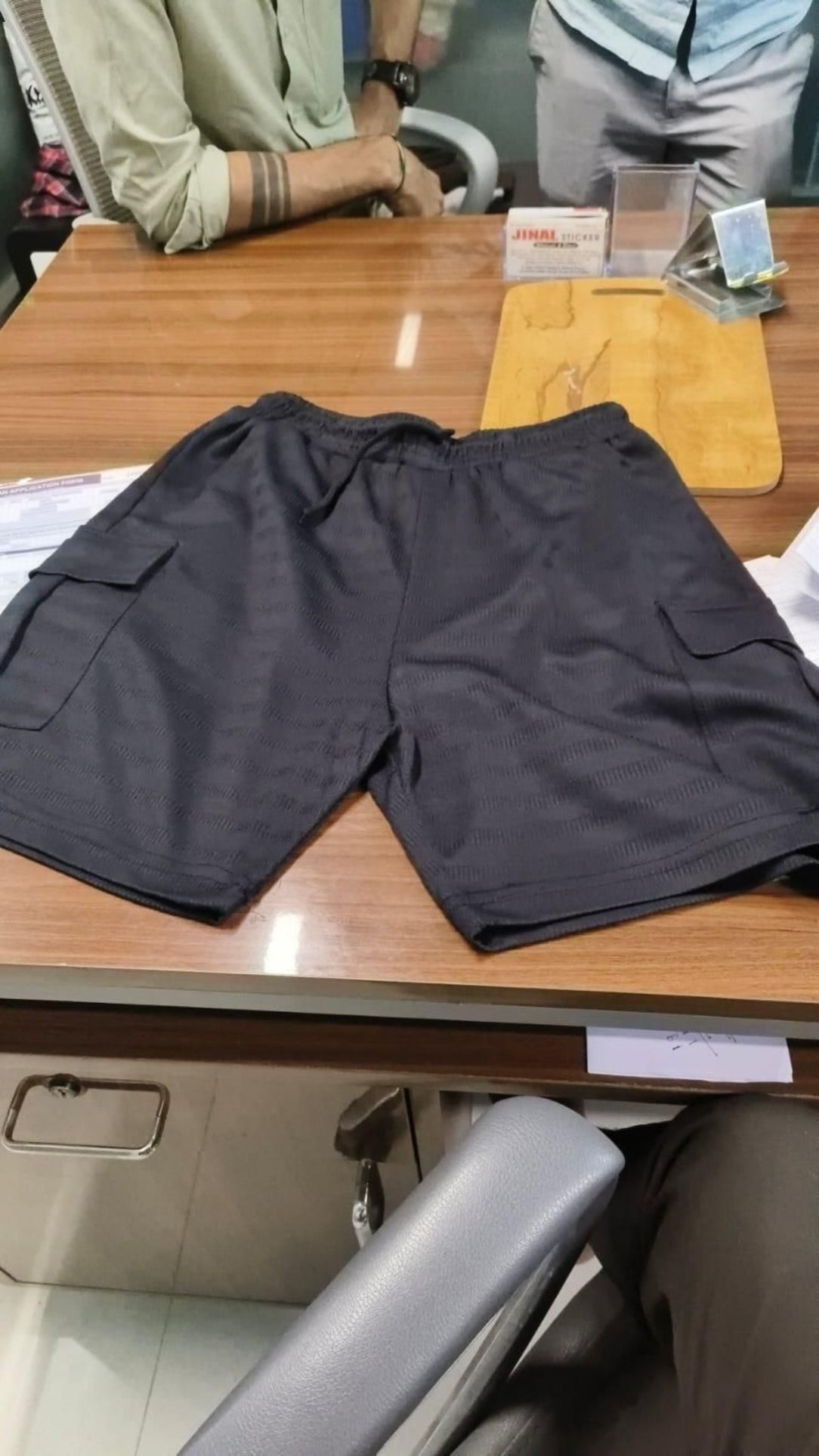 Black shorts on a wooden table with a person in the background
