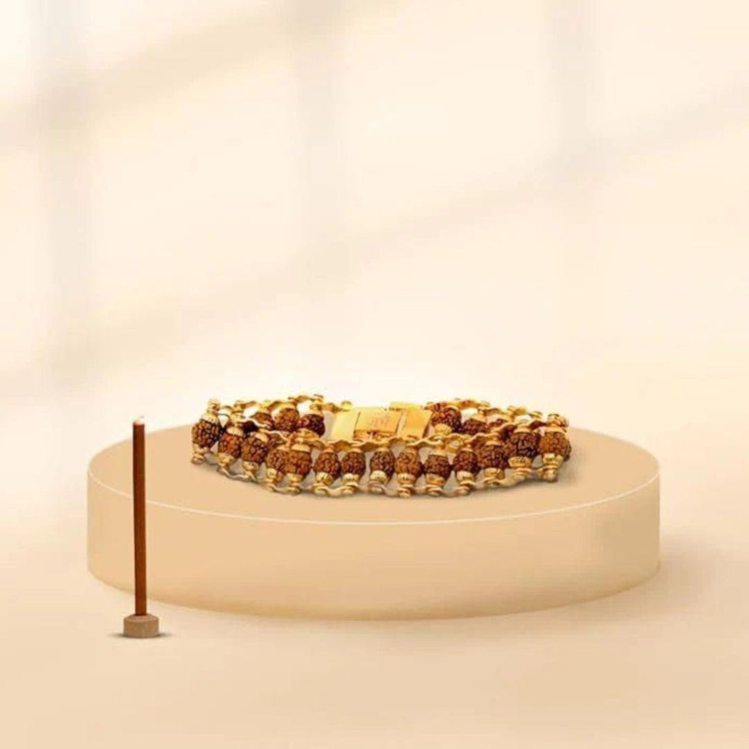 Gold and brown beaded bracelet on a beige stand with a soft beige background
