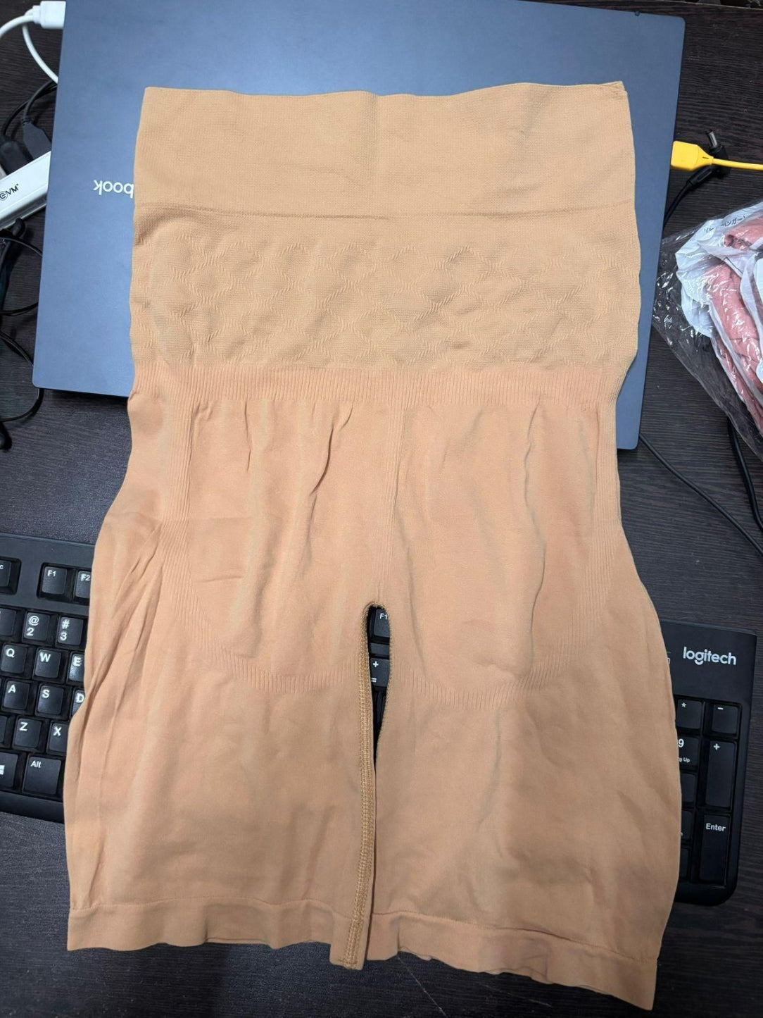 Beige sweatshirt on a desk with a keyboard and computer mouse in the background