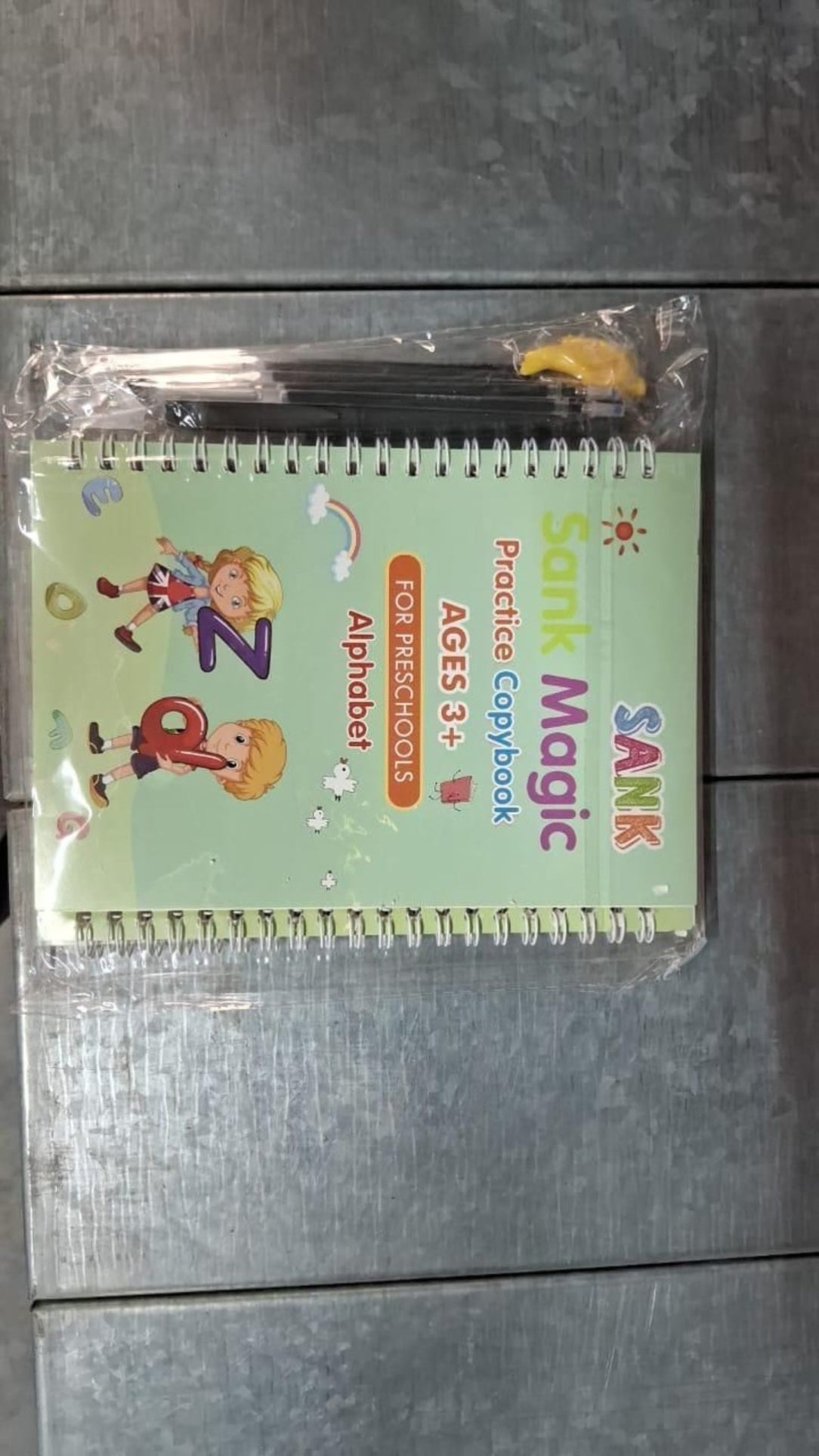 Children's practice copybook with colorful design on a metallic surface