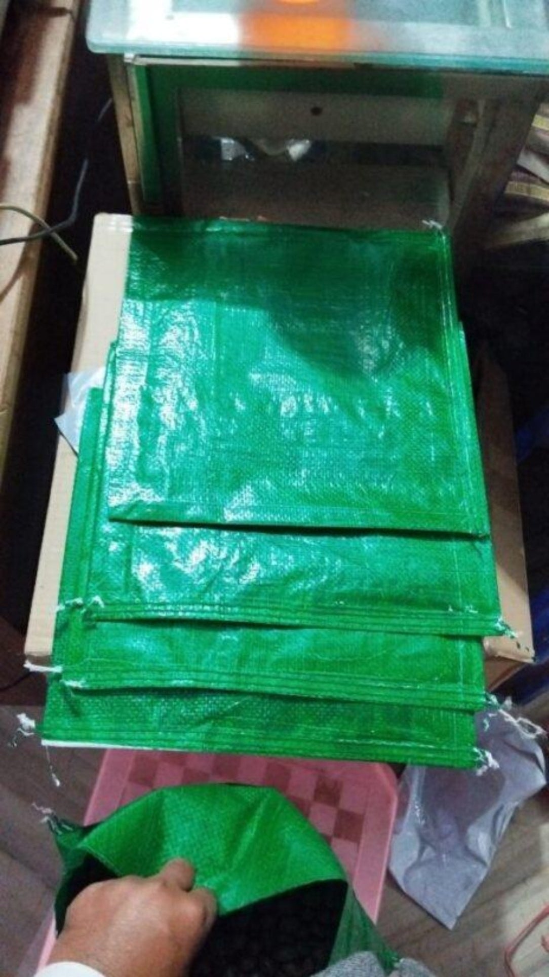 Stack of green plastic sheets on a table with a hand reaching for one.
