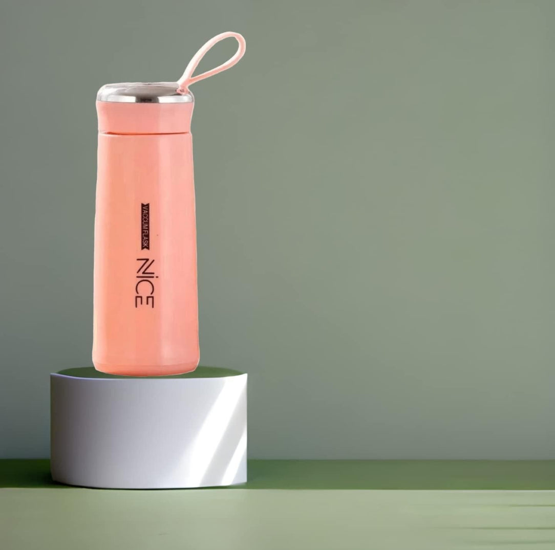 Pink water bottle with 'NICE' branding on a green surface and gray background