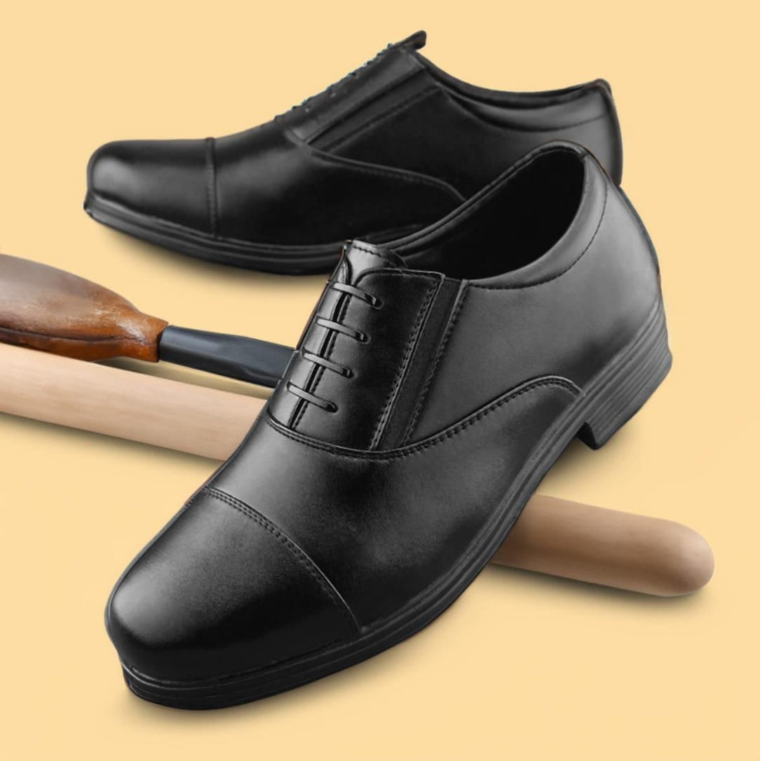 Black dress shoes on a beige background with wooden shoes and a wooden stick.
