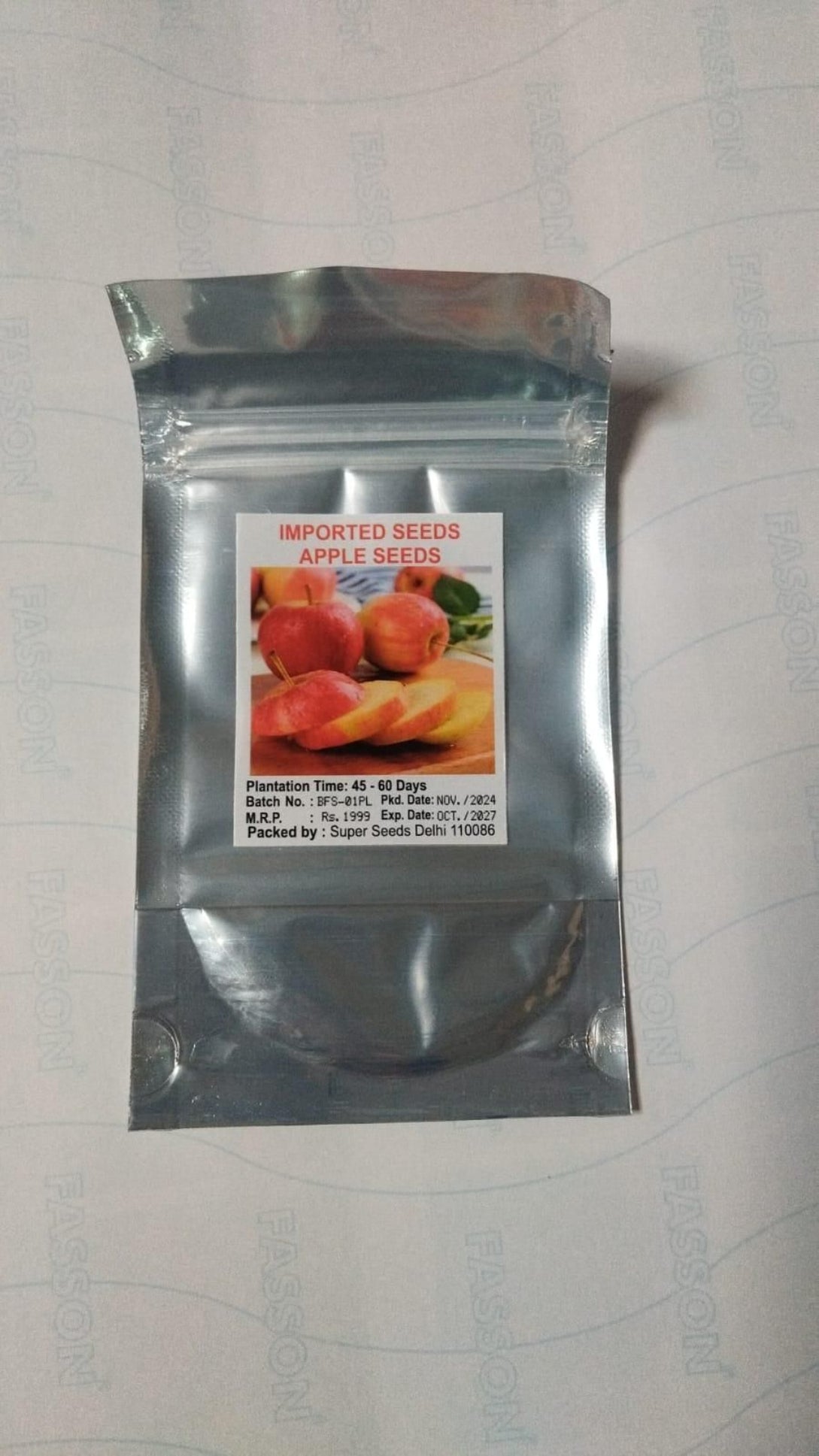 Silver package of imported apple seeds on a light gray background