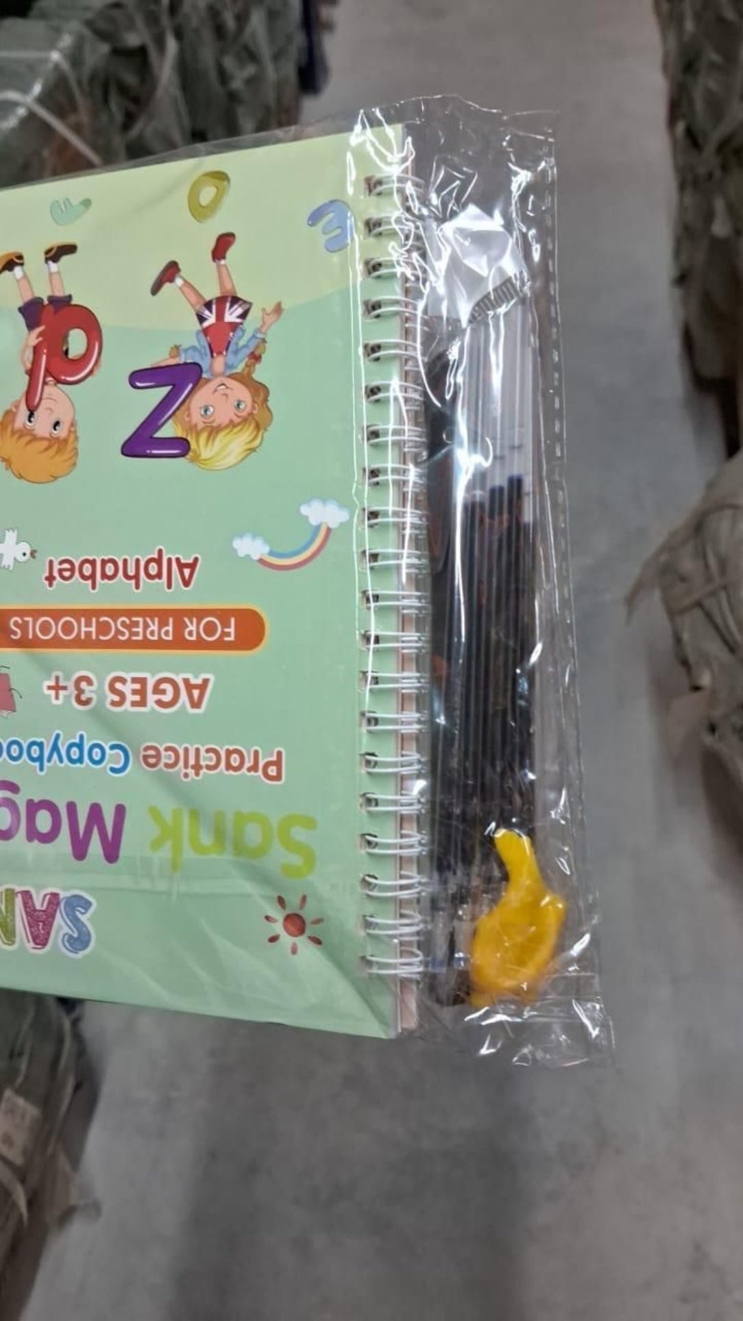 Book with alphabet stickers and a pen on a surface