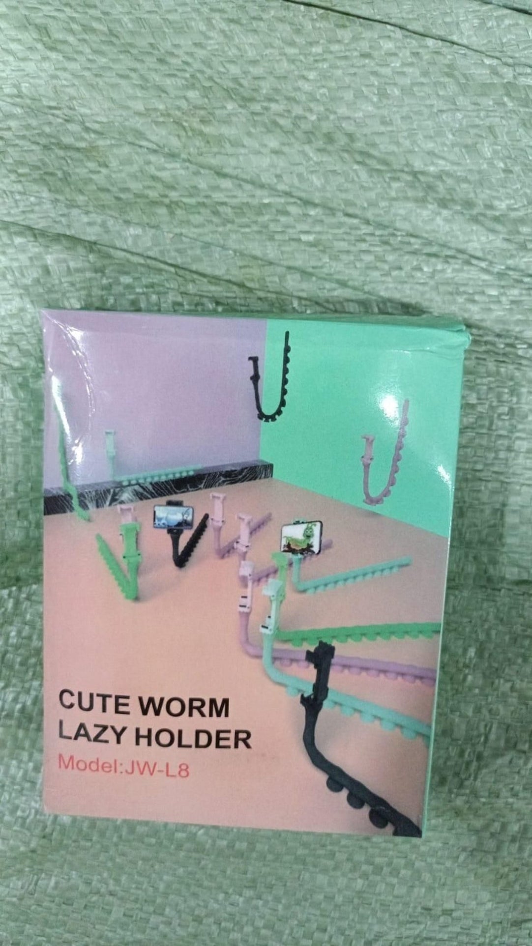 Product packaging of a 'Cute Worm Lazy Holder' on a textured green surface