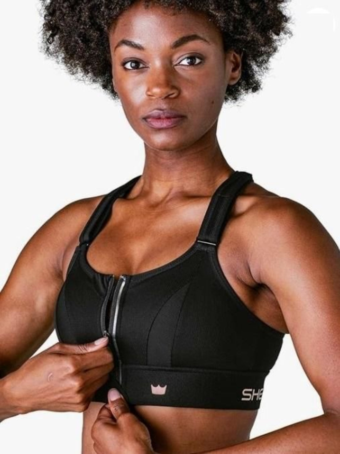 Woman wearing a black sports bra with a visible brand logo on a neutral background