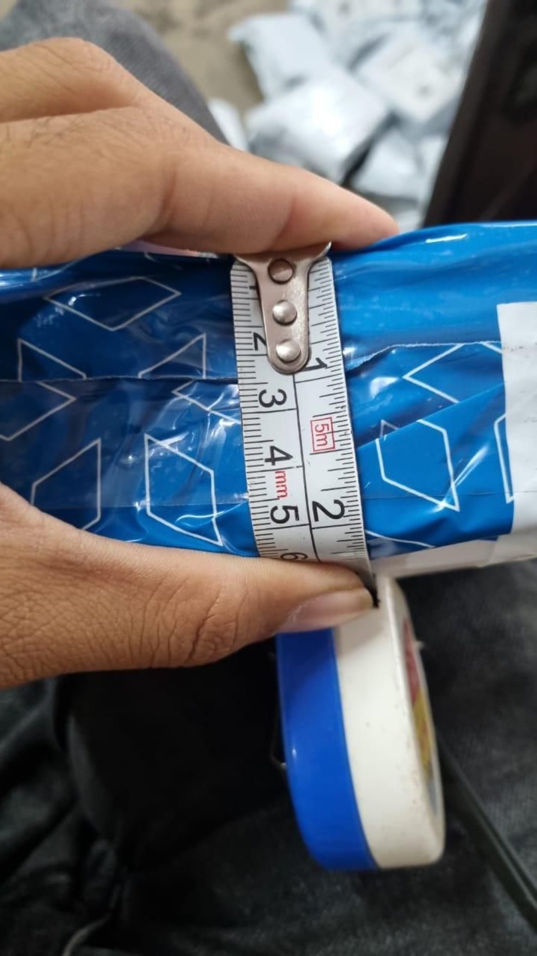 Person measuring a blue and white object with a tape measure