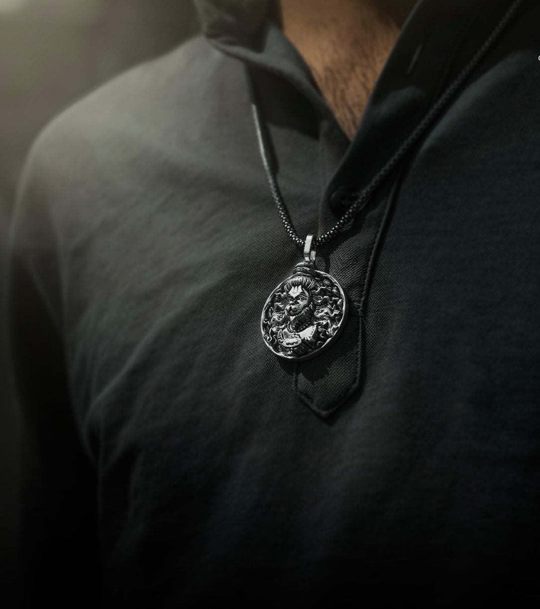 Close-up of a silver necklace with a pendant on a dark shirt