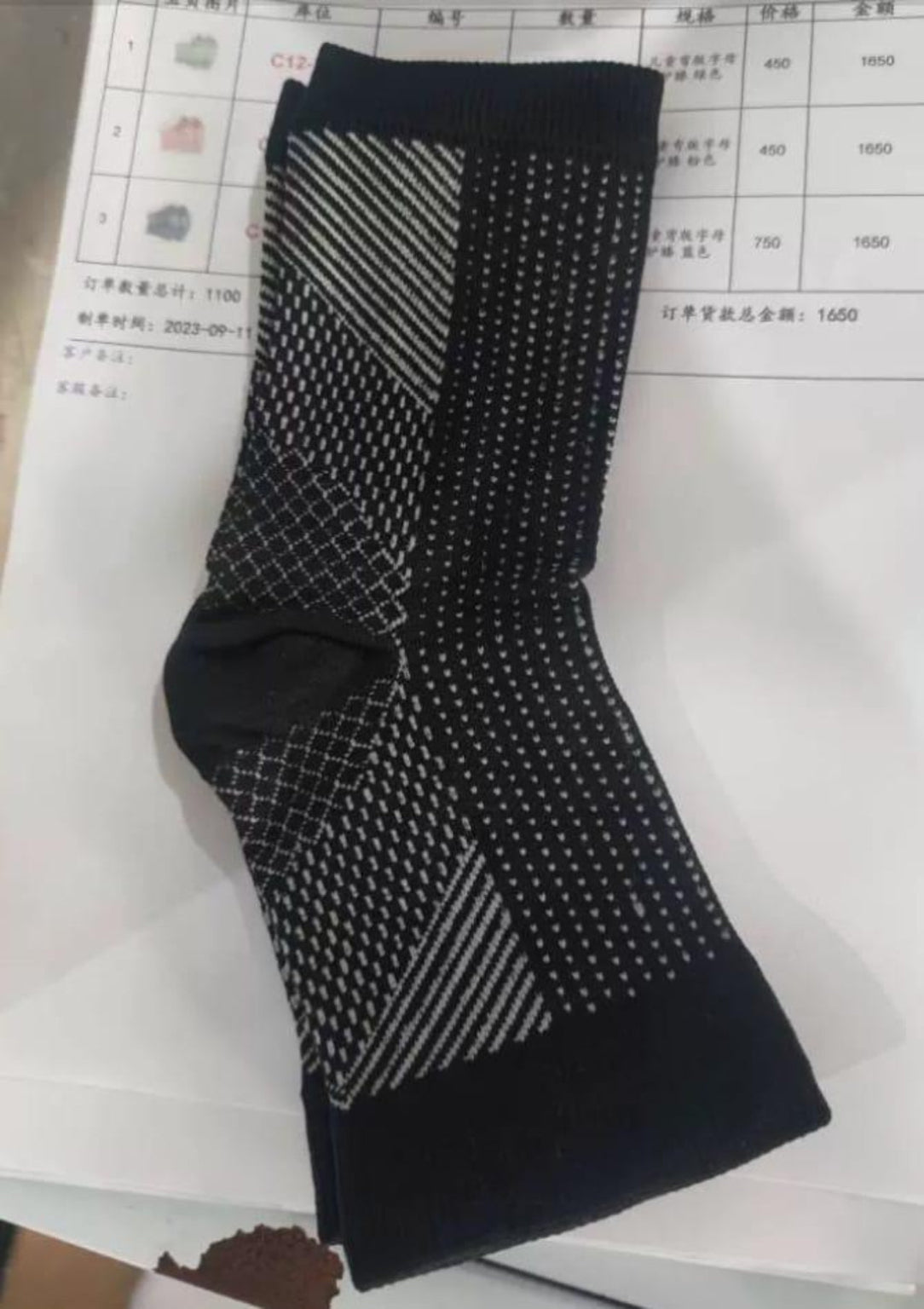 Black and gray patterned socks on a white surface with a blurred background