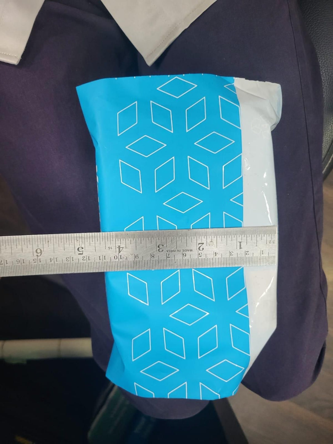 Blue geometric-patterned pouch with a ruler for scale on a dark background