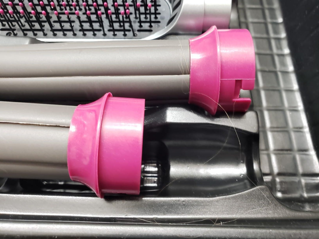 Hair dryer with pink nozzles on a metallic surface
