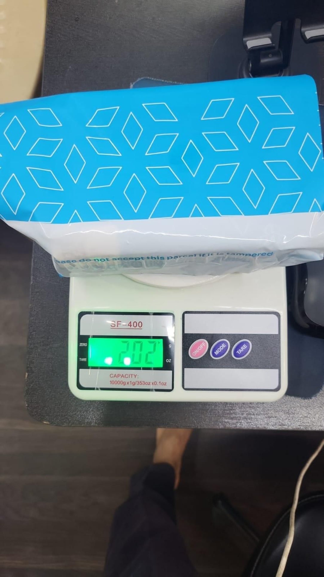 Packaged product on a digital scale with a blue and white geometric patterned label.