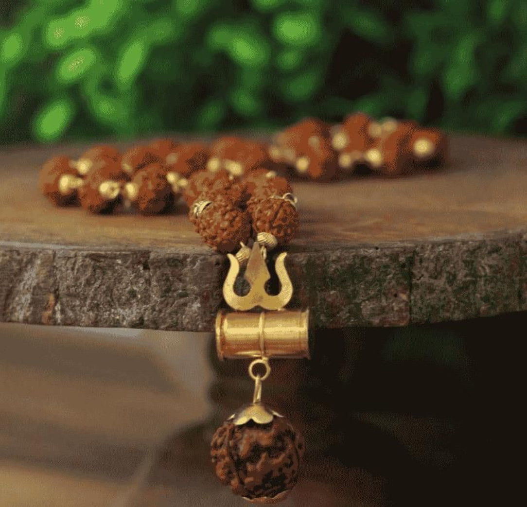 Rudraksha beads with a gold pendant on a wooden surface