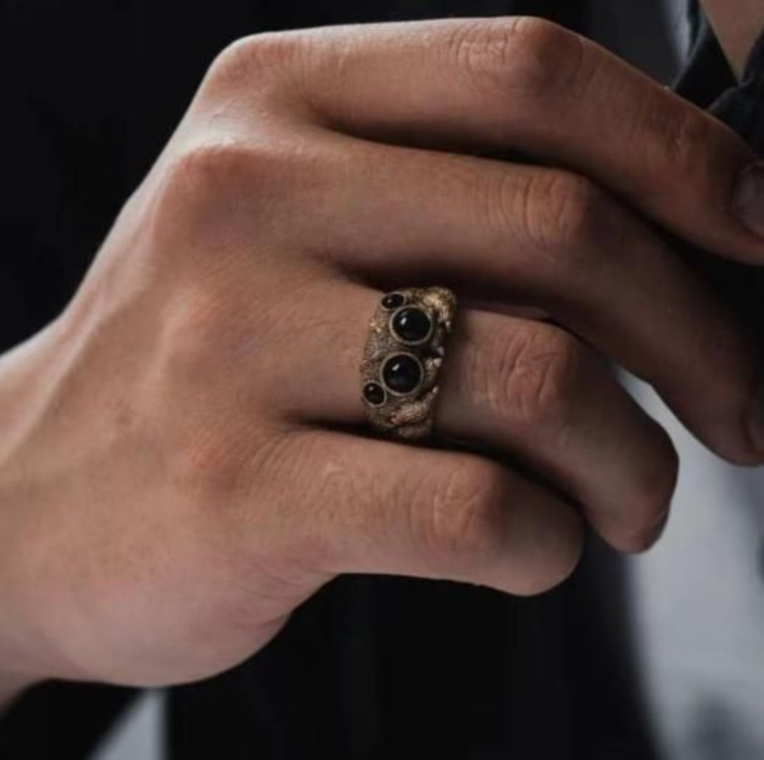 Hand wearing a ring with black stones on a blurred background