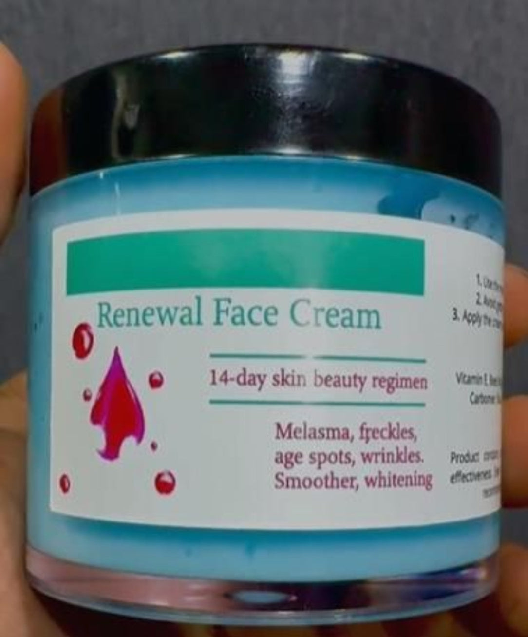 Jar of Renewal Face Cream held by a hand with a gray background
