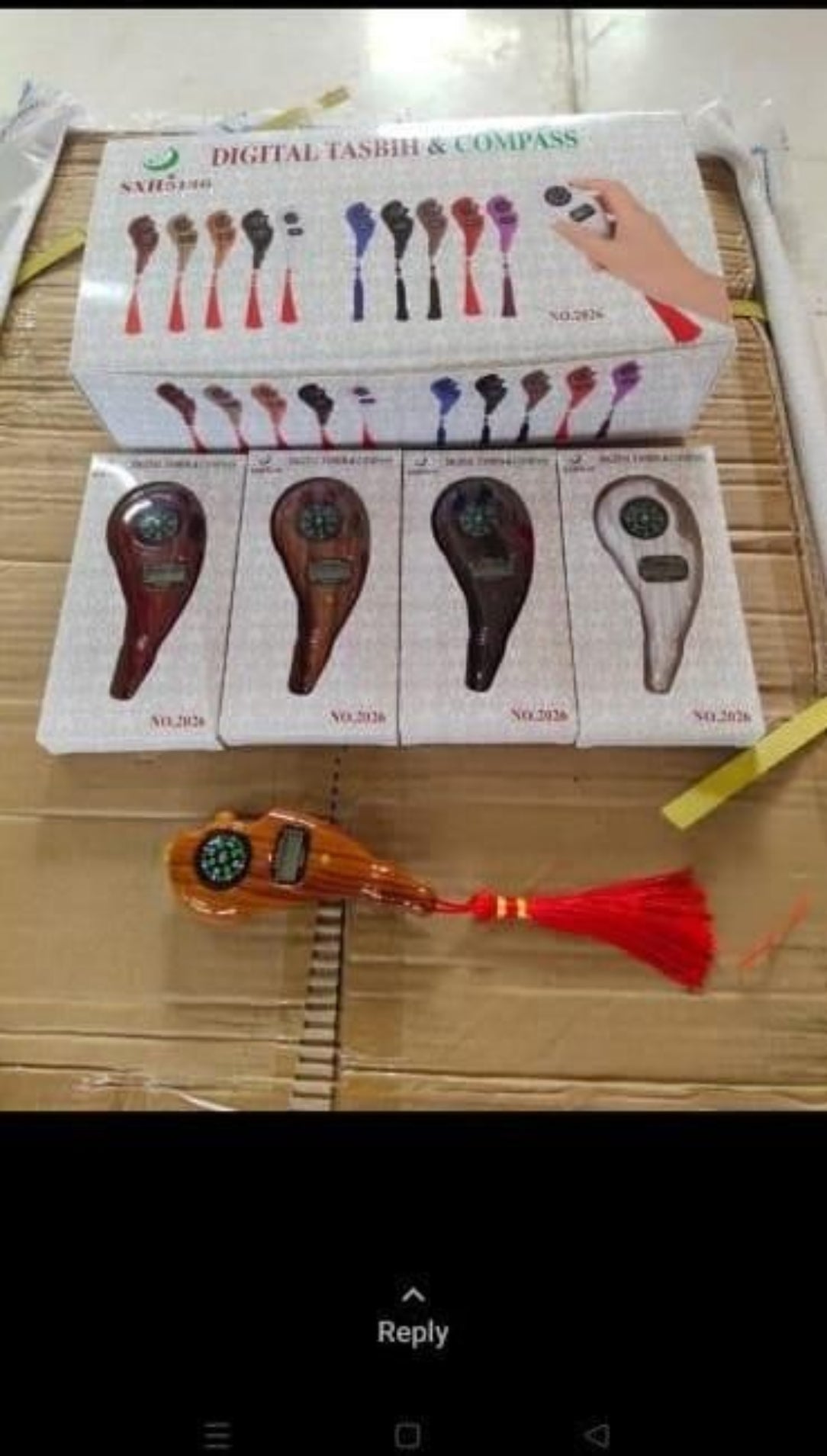 Digital compass and tassel on a wooden surface with packaging in the background.