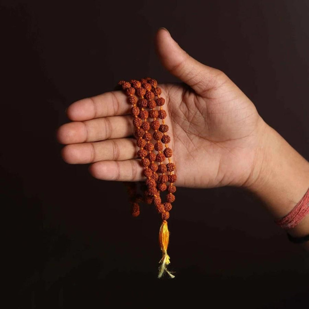 Hand holding a string of prayer beads against a dark background