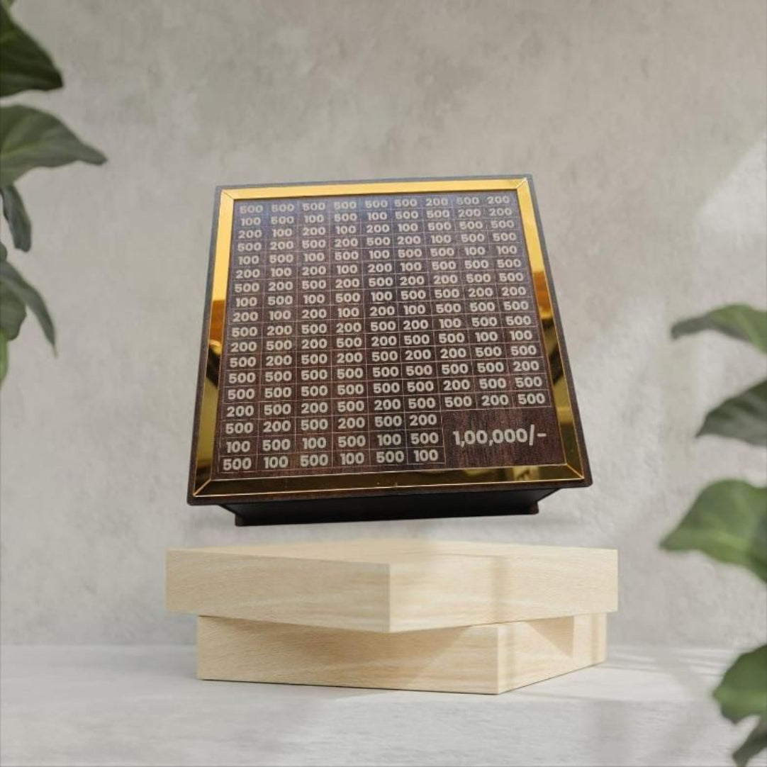 A wooden piggy bank with a gold-colored label on top displaying numbers, placed on a wooden surface with plants in the background.