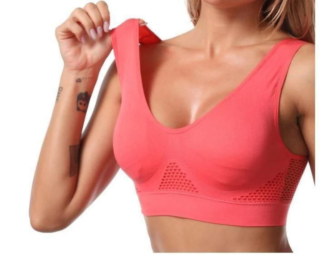 Person wearing a coral sports bra on a white background
