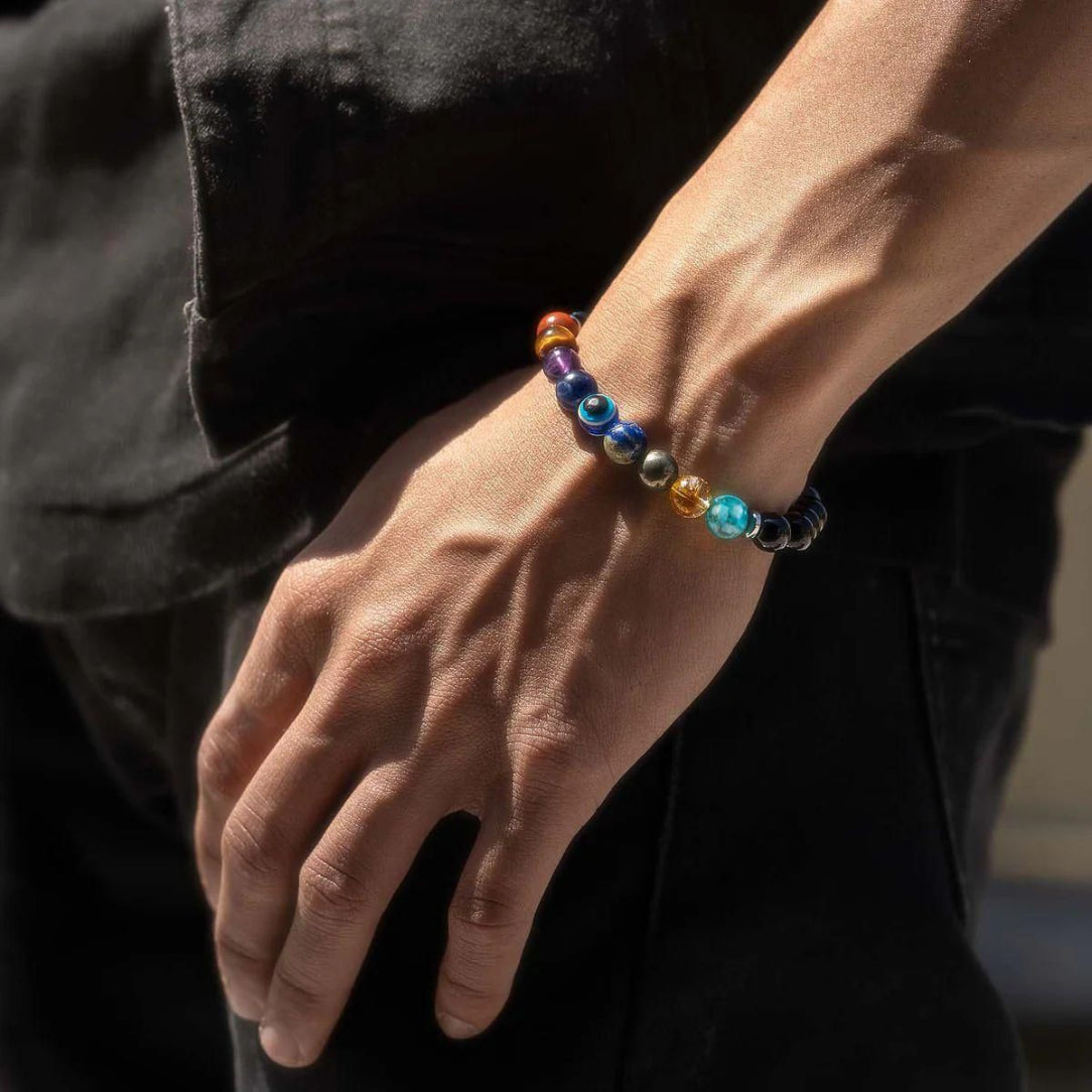 Close-up of a hand wearing a colorful beaded bracelet against a dark background