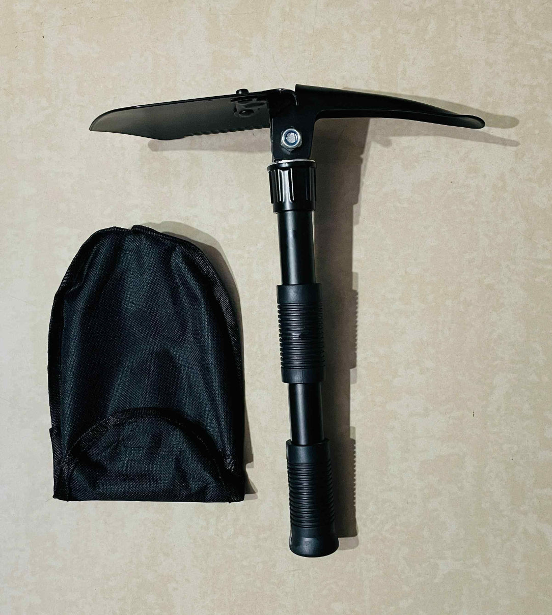 Black folding ice axe with sheath on a beige background