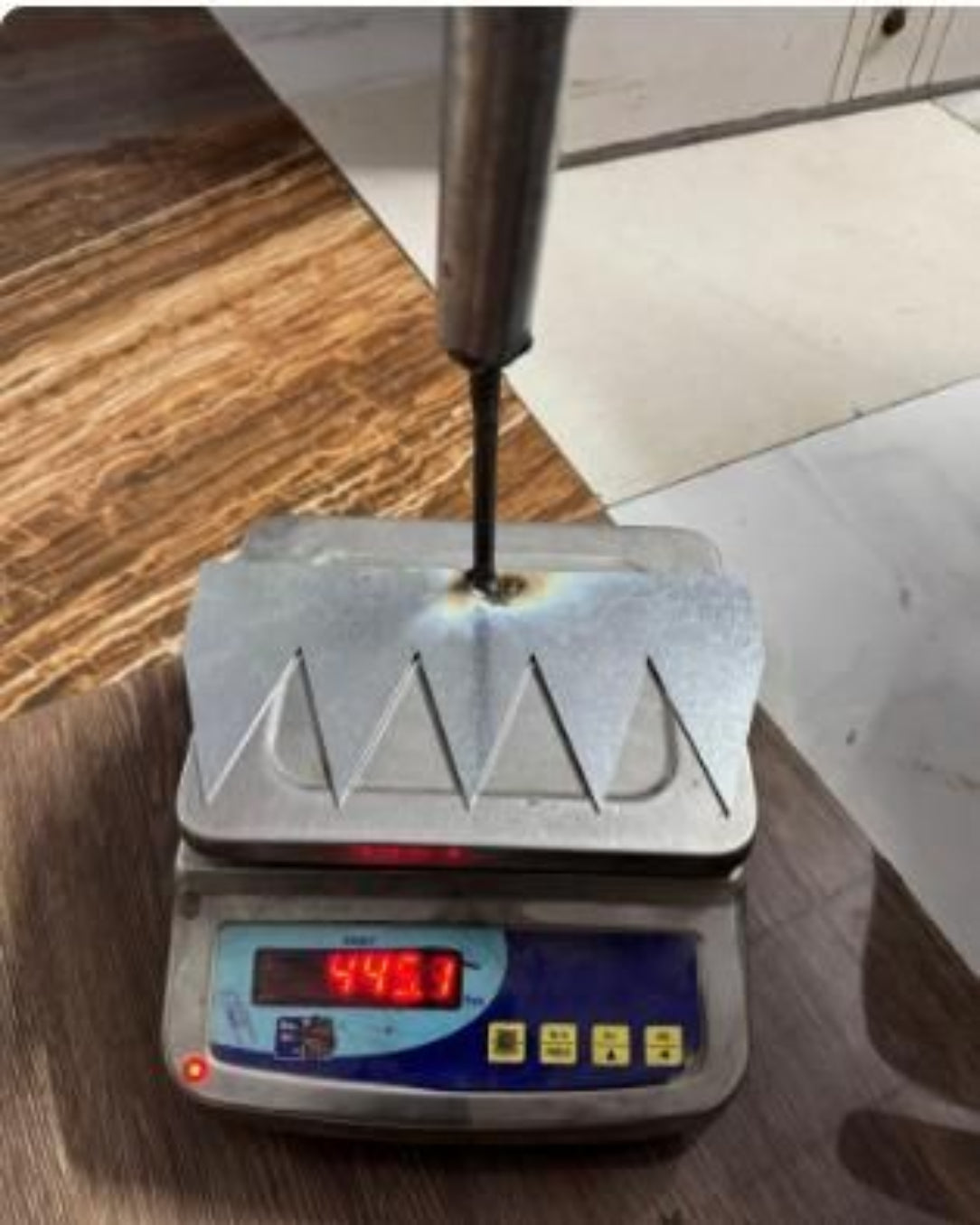 Digital scale with a metal object on it, showing a weight reading.