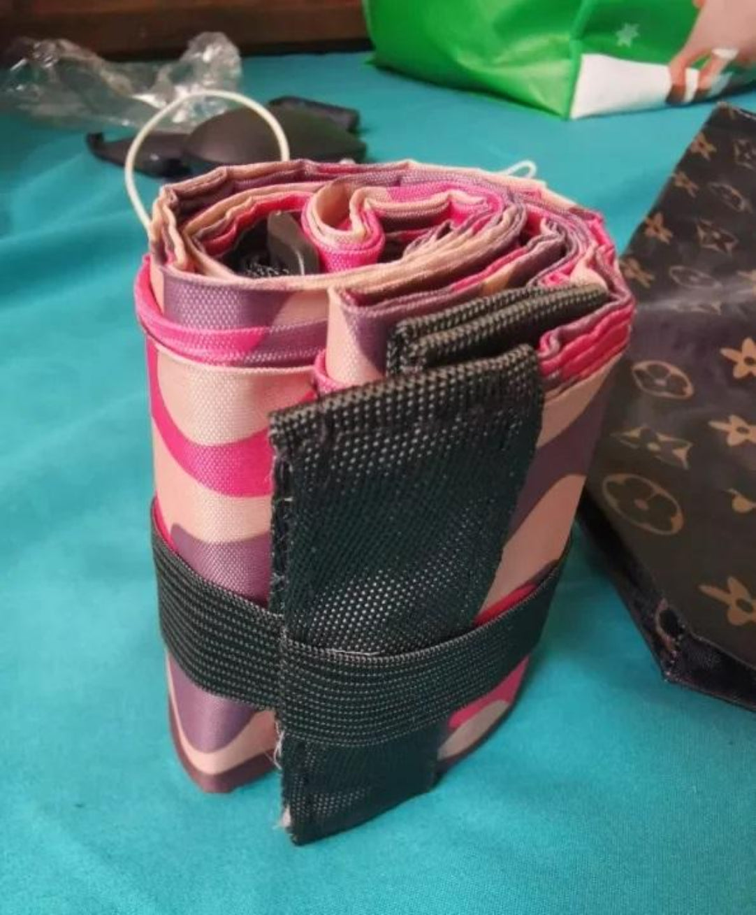 Roll of pink and black striped fabric with a black strap on a blue surface