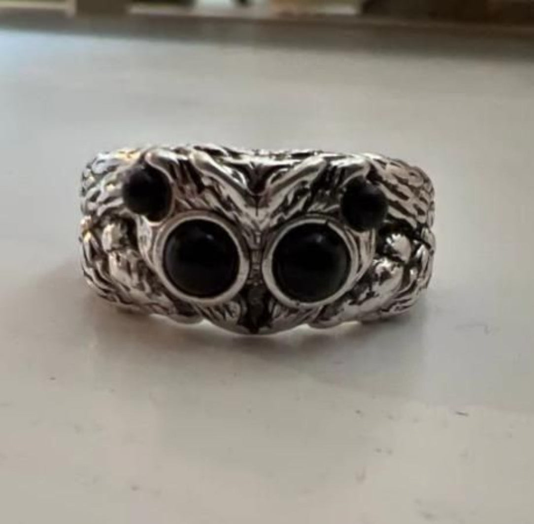 Silver knuckle duster ring with black stones on a light gray surface