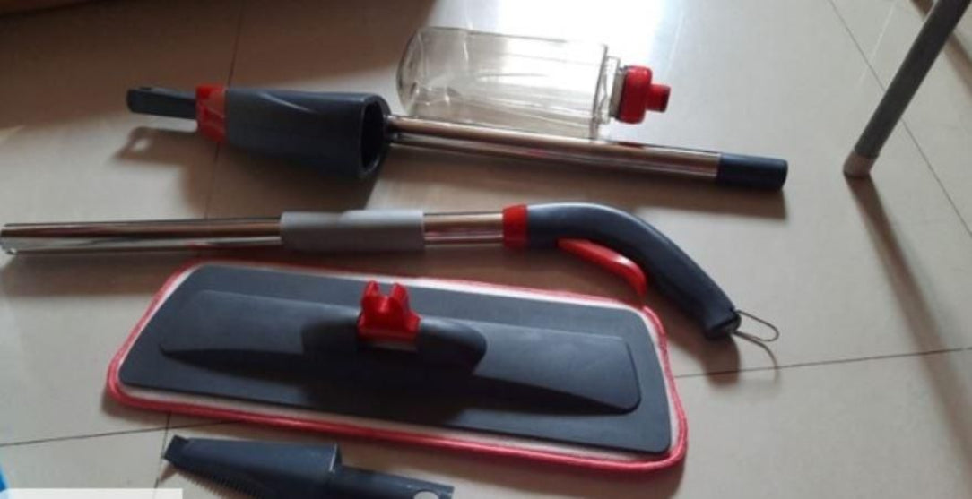Cleaning tools including a brush, squeegee, and bottle on a tiled floor.