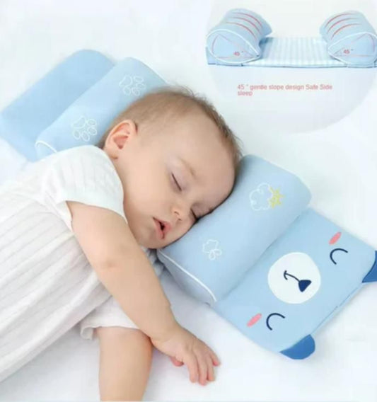 Baby sleeping on a blue pillow with cartoon designs on a white background
