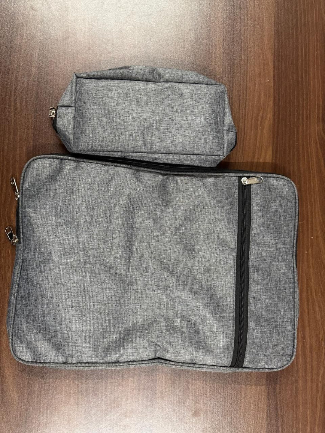 Two gray zippered pouches on a wooden surface