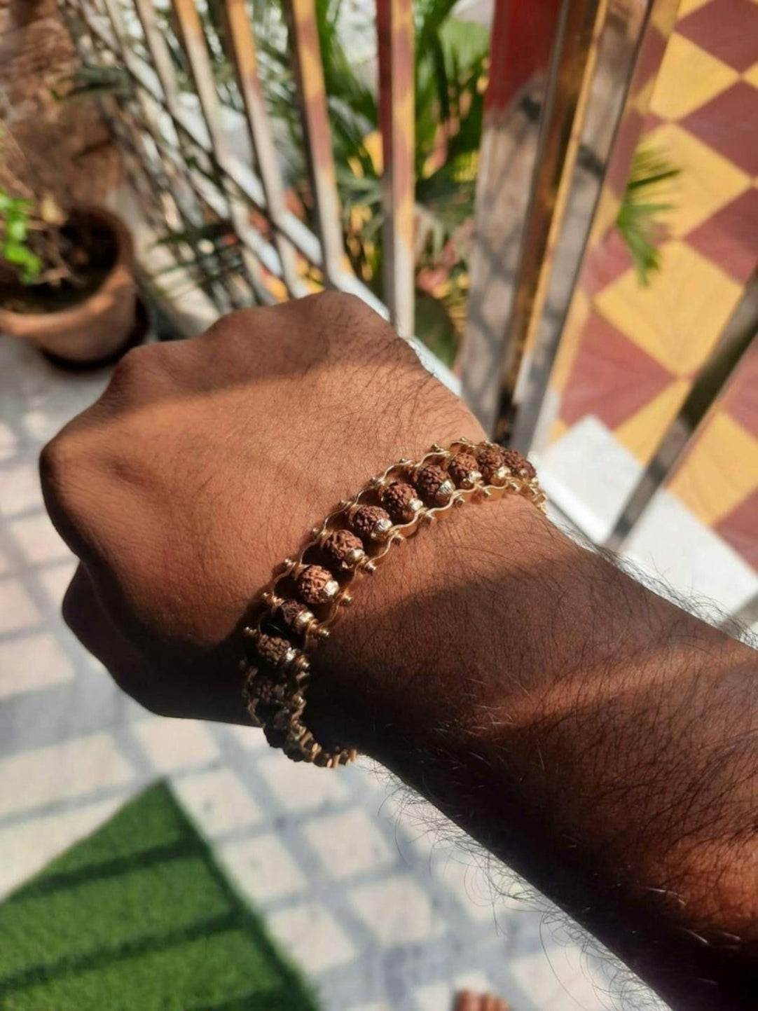 Hand wearing a bracelet with a blurred outdoor background