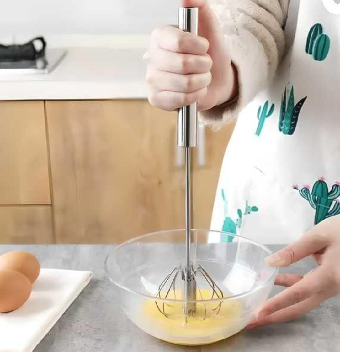 Person whisking eggs in a bowl with an immersion blender in a kitchen setting.