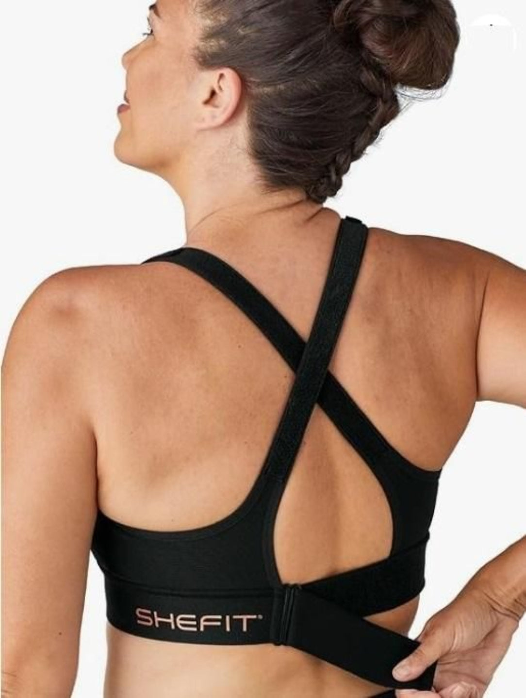 Black sports bra with criss-cross straps worn by a person, on a white background