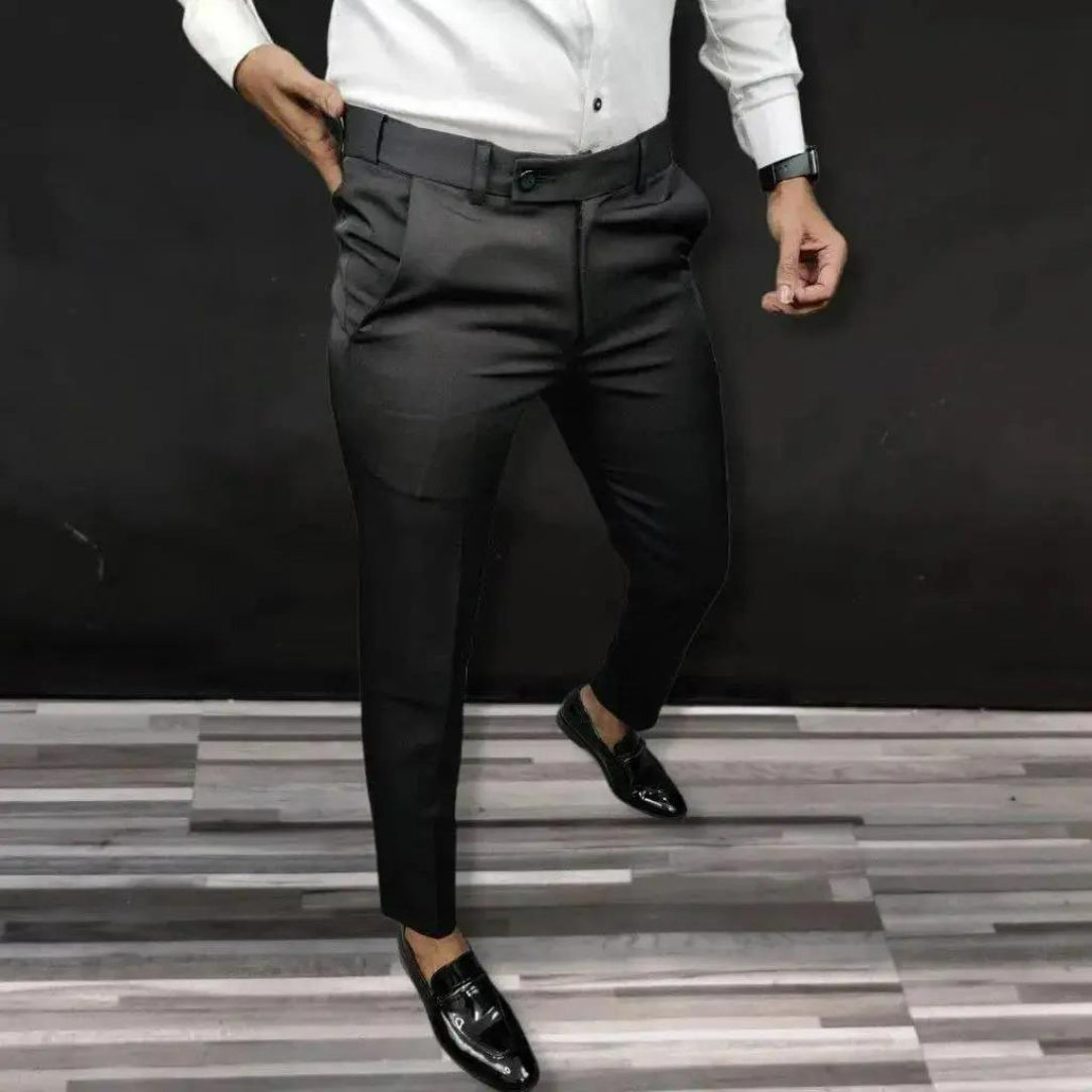Person wearing a white shirt and black pants with black shoes on a gray and black striped floor.