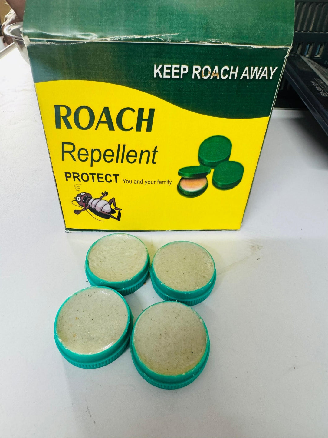 Roach Repellent packaging with four green and beige discs on a white surface