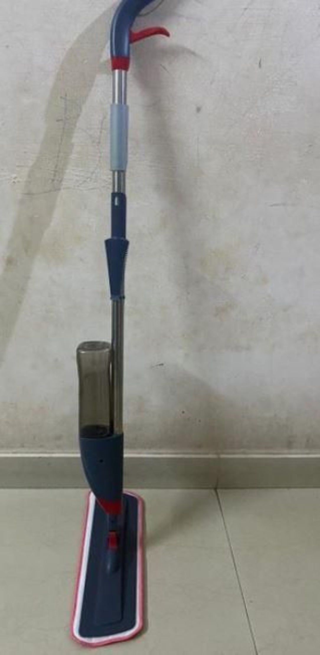 Mop leaning against a wall on a tiled floor