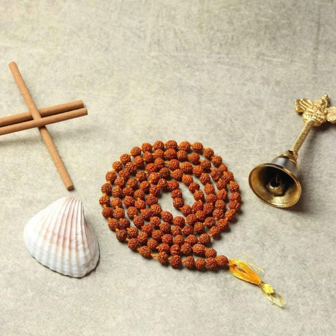 Meditative objects including a rosary, shell, wooden cross, and bell on a textured surface.