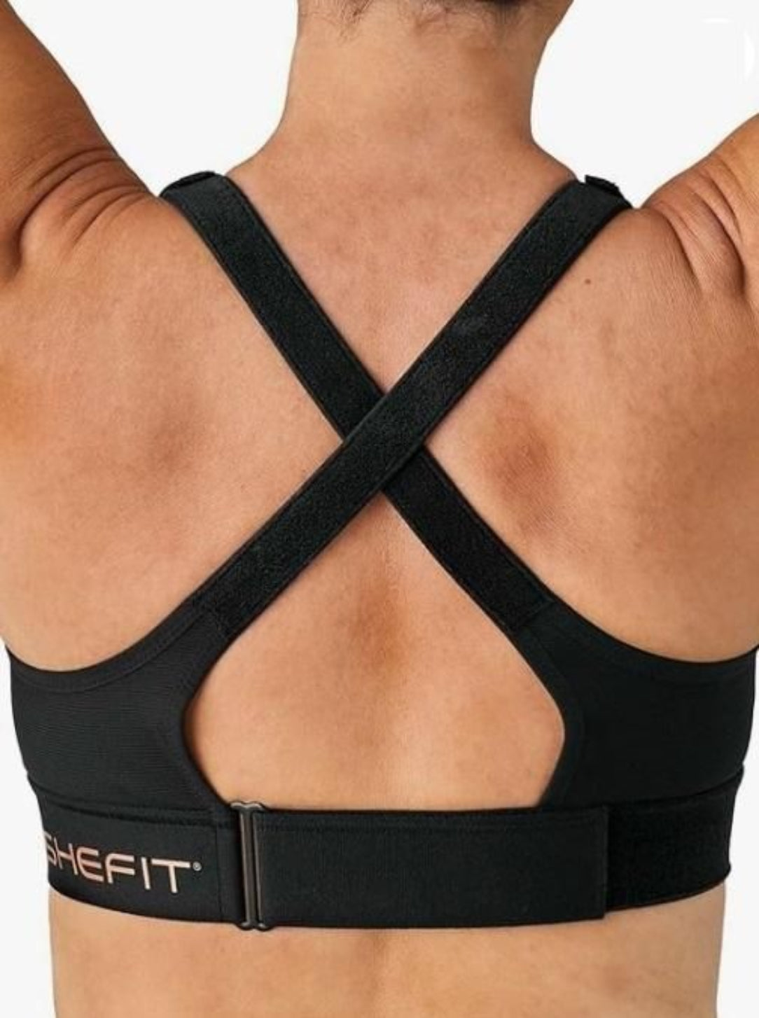 Black sports bra with criss-cross straps on a person, featuring the SHEFIT brand.