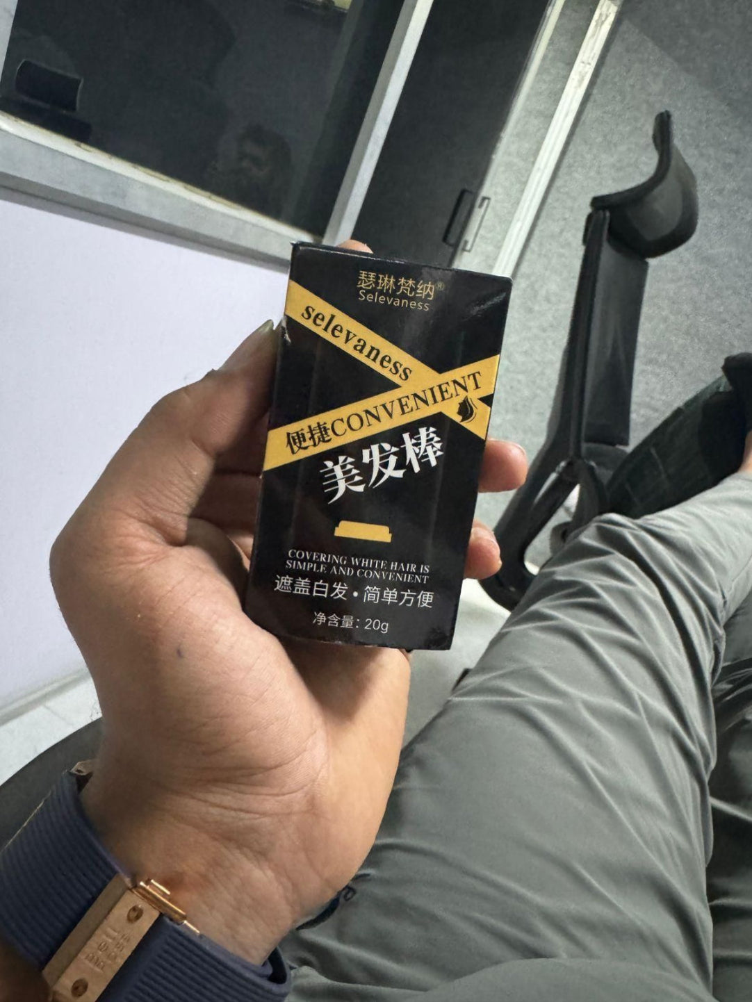 Hand holding a black and yellow package labeled 'selevaness' with a blurred background.