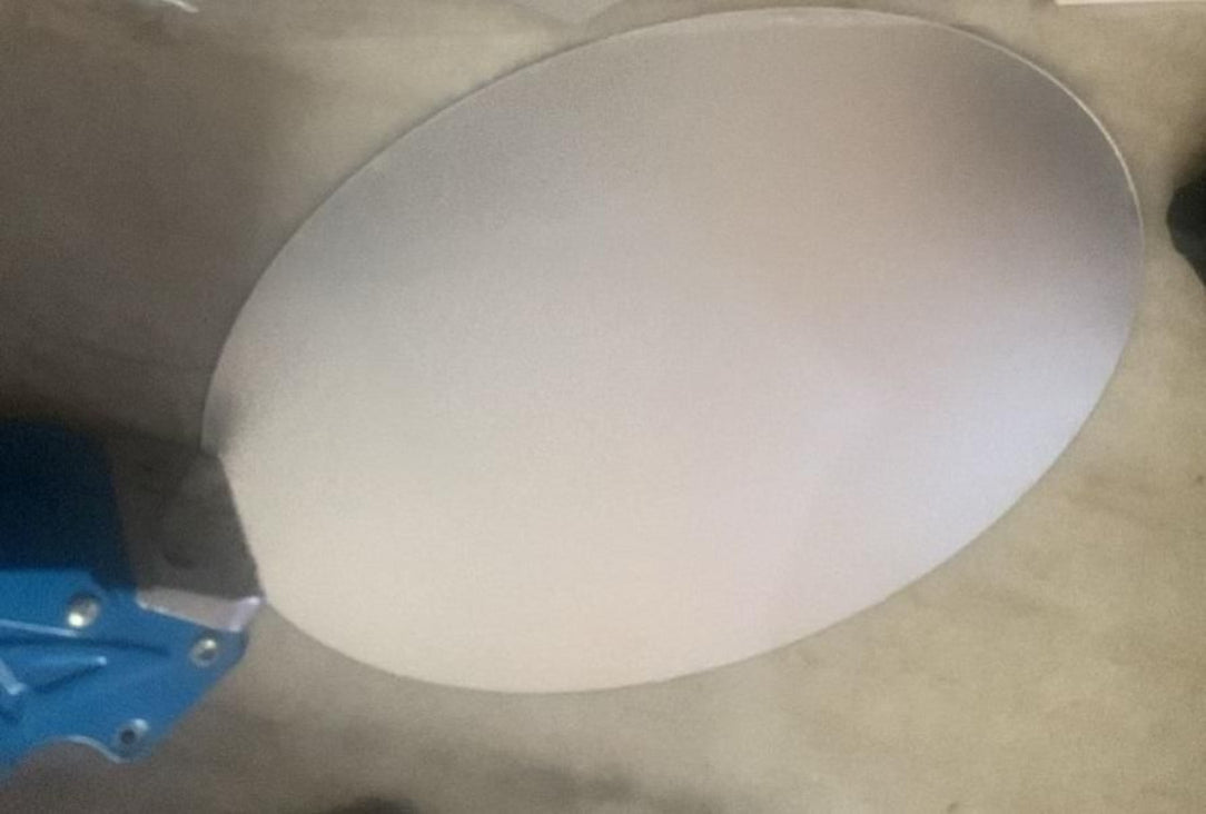 Round metal object on a concrete surface with a blue tool nearby