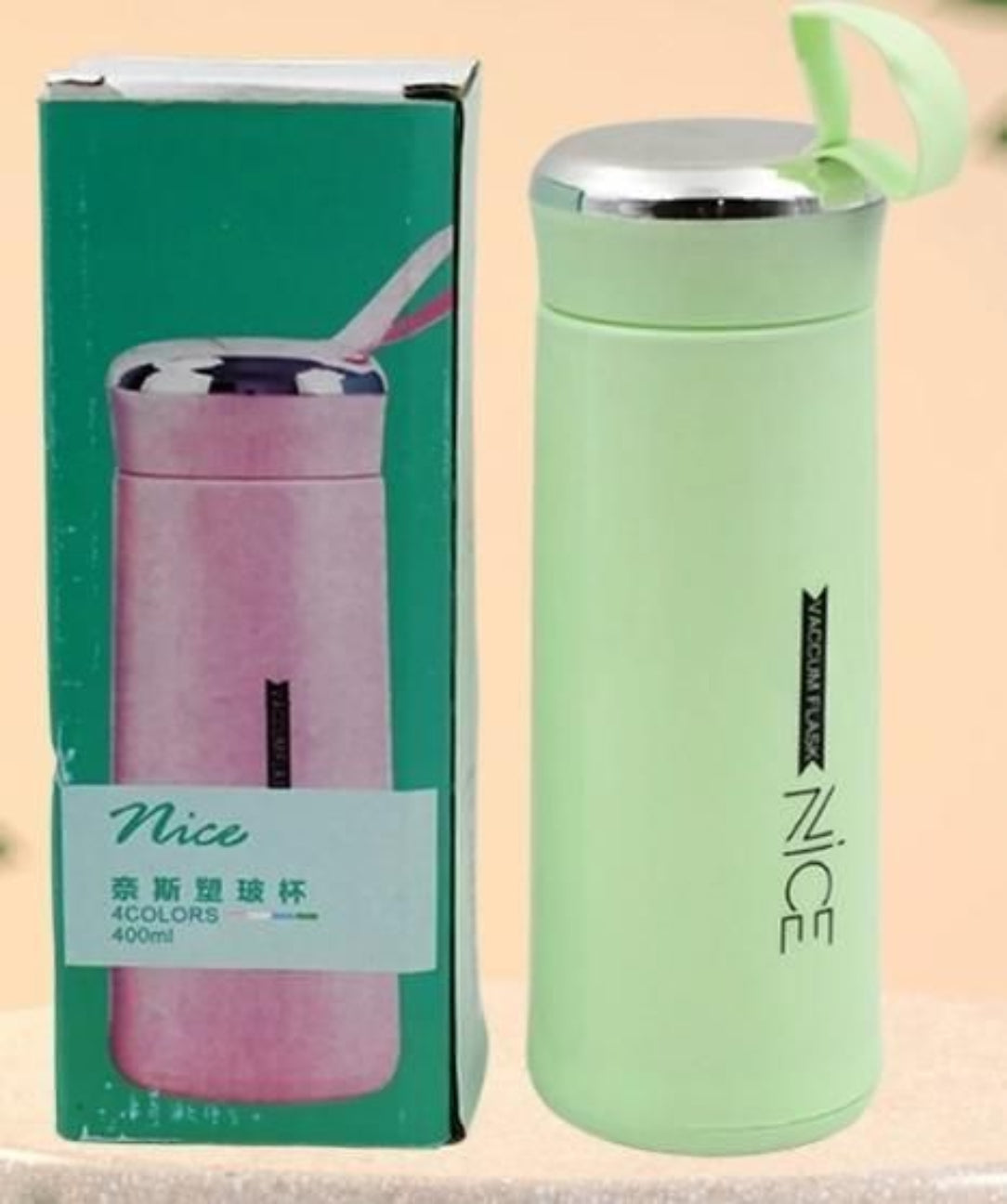 Green thermos with 'Nice' branding next to its packaging on a beige background