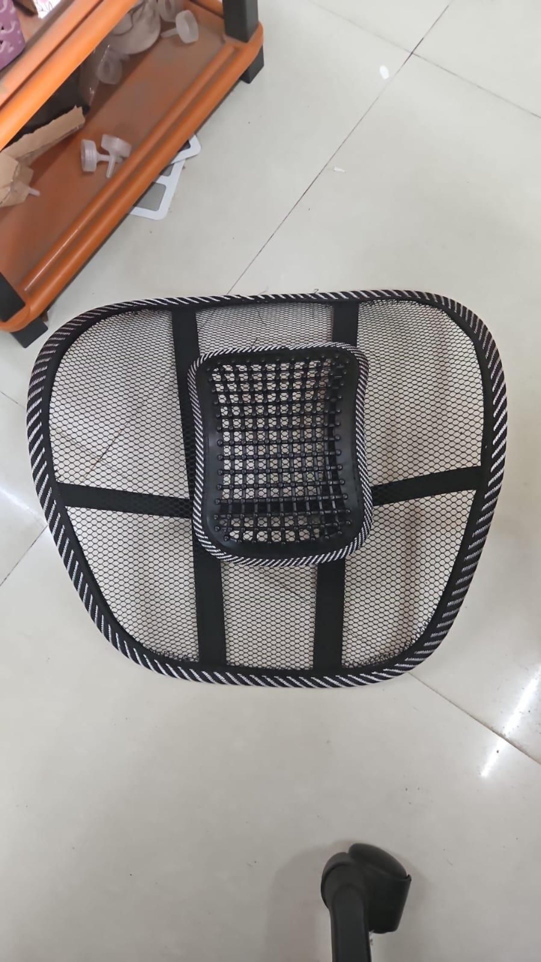 Black mesh chair pad on a tiled floor