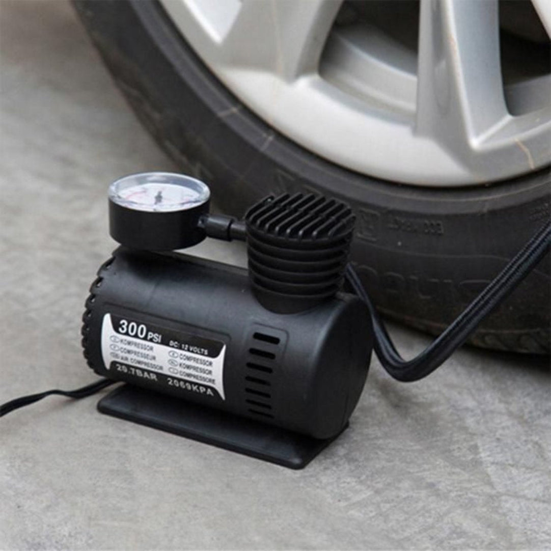 Car tire inflator with a gauge next to a car tire on a concrete surface