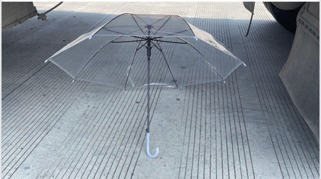 Clear umbrella on a tiled floor with a car in the background
