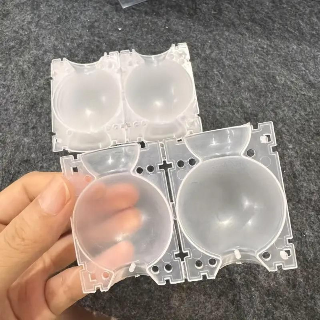 Clear plastic component held by a hand on a dark surface