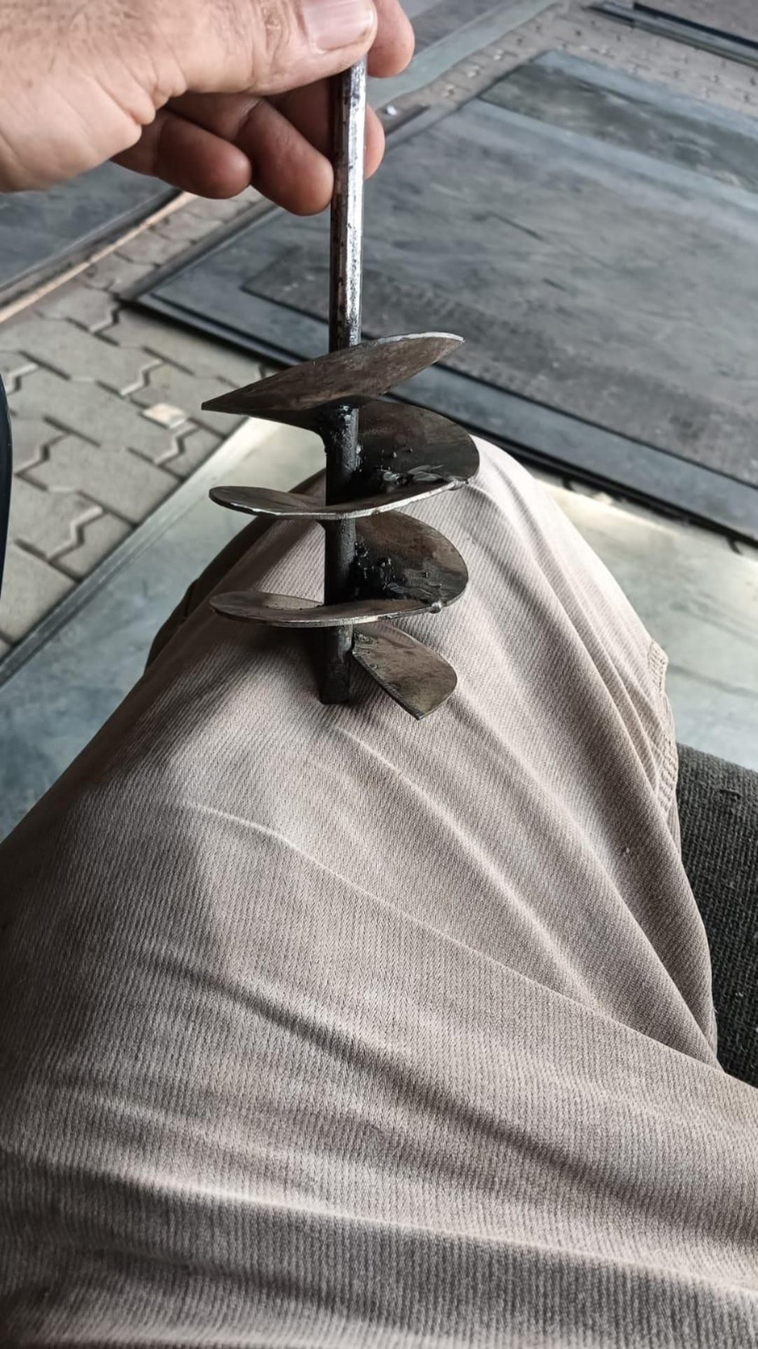 Person using a drill to install a metal anchor into a concrete surface.